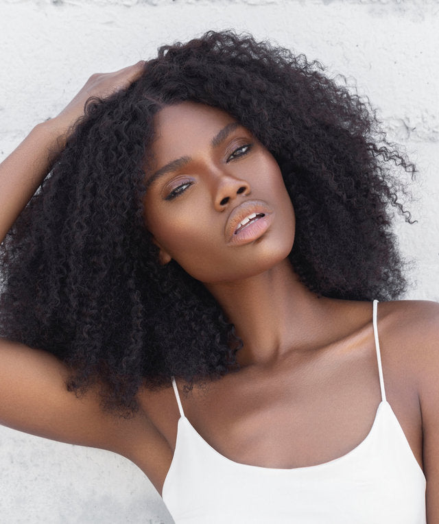 Black woman wearing natural curly wig extensions from Nahara’s Curls, styled in bold, voluminous coils. Model showcasing natural hair extensions for Black women, featuring defined curls and full texture.