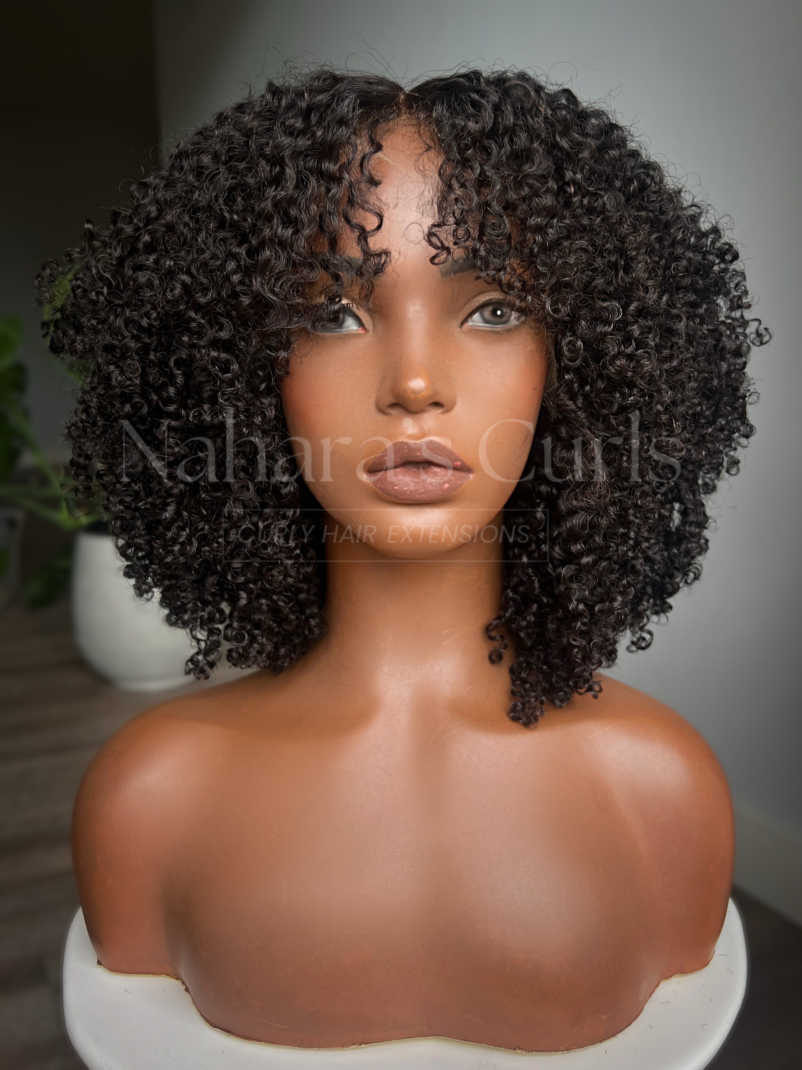 Mannequin head with curly black hair on a neutral background