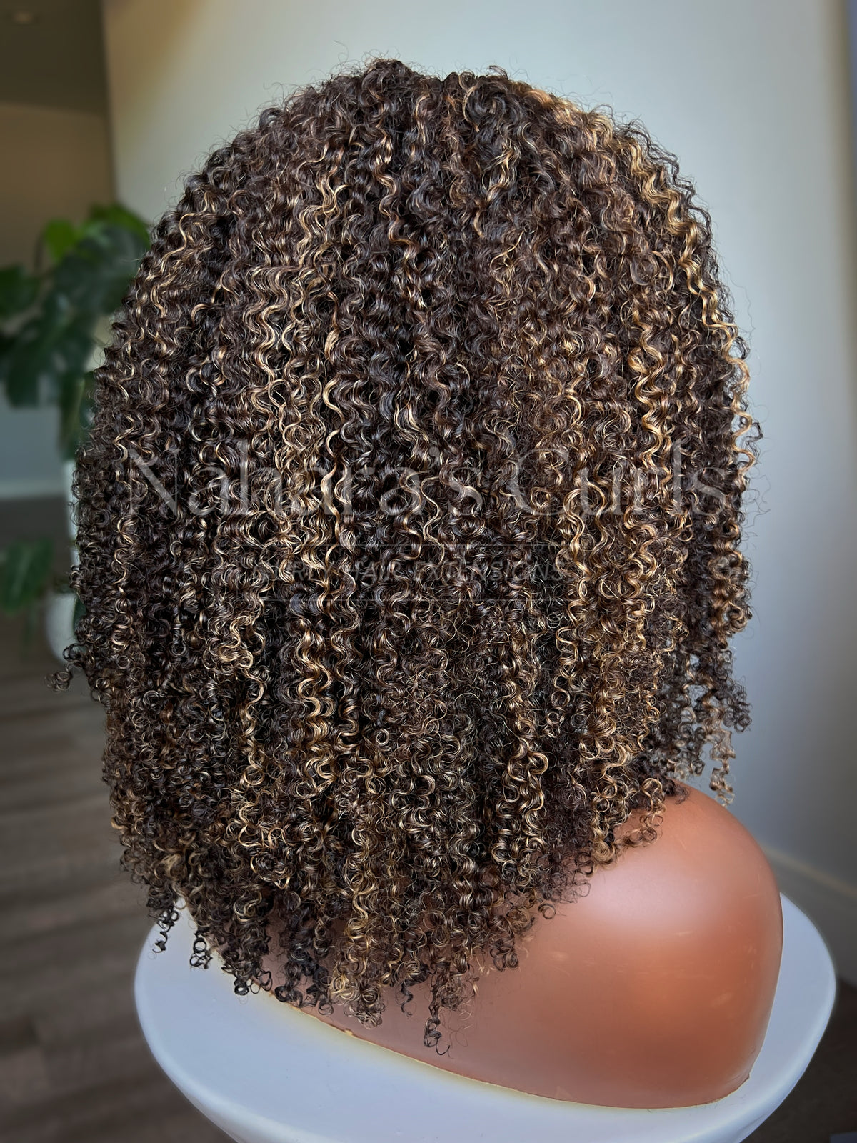 Back view of kinky curly U-part wig with brown and caramel highlights and rounded layered shape