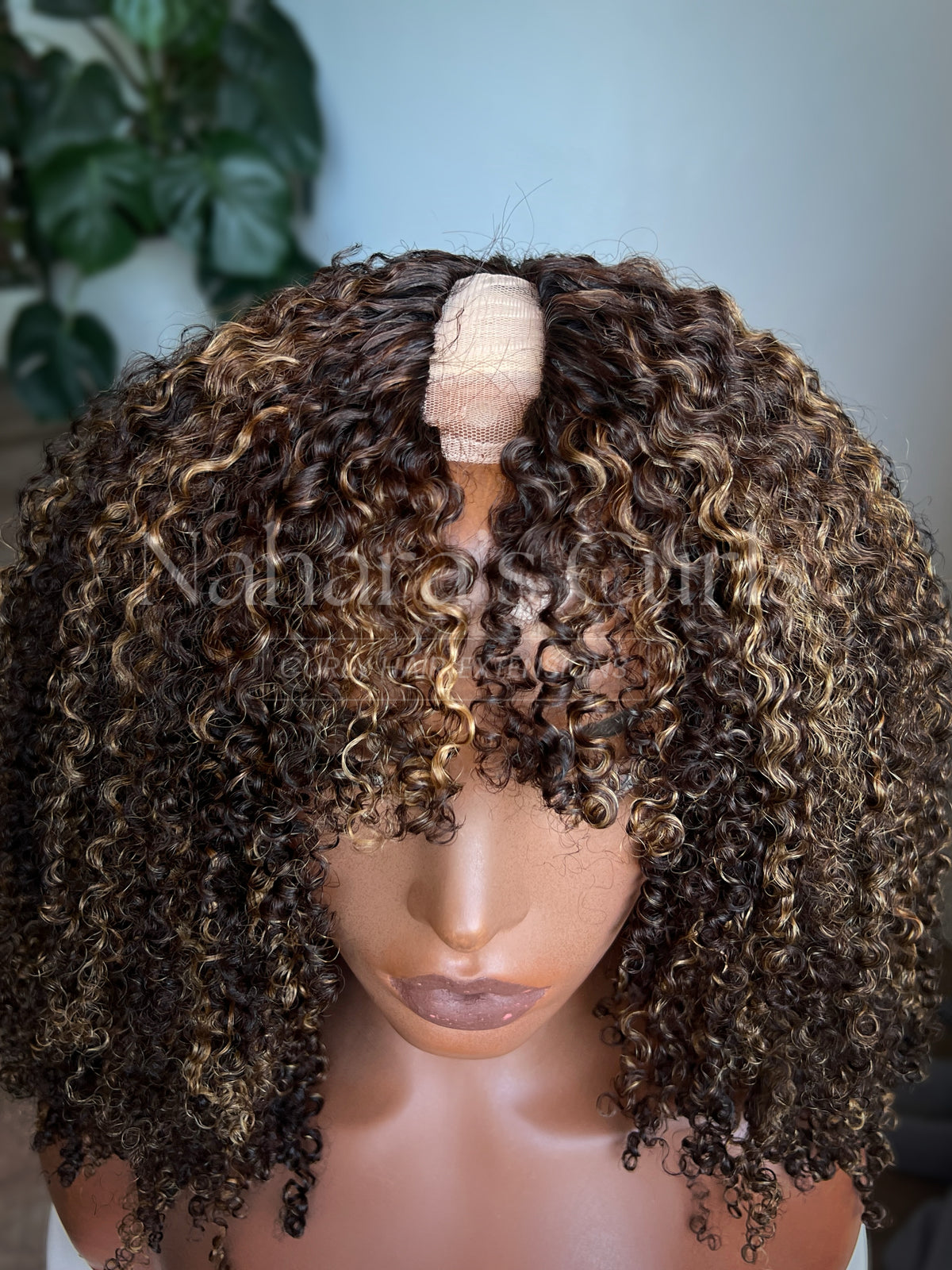 Close-up of highlighted curly human hair U-part wig showing defined coils and brown caramel color